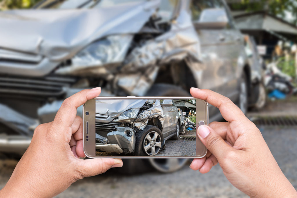 A phone taking a picture of a car after a wreck