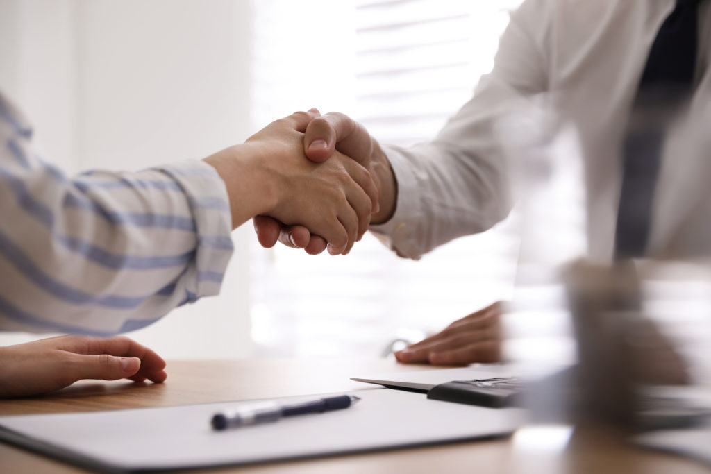 Business people shaking hands in office, closeup